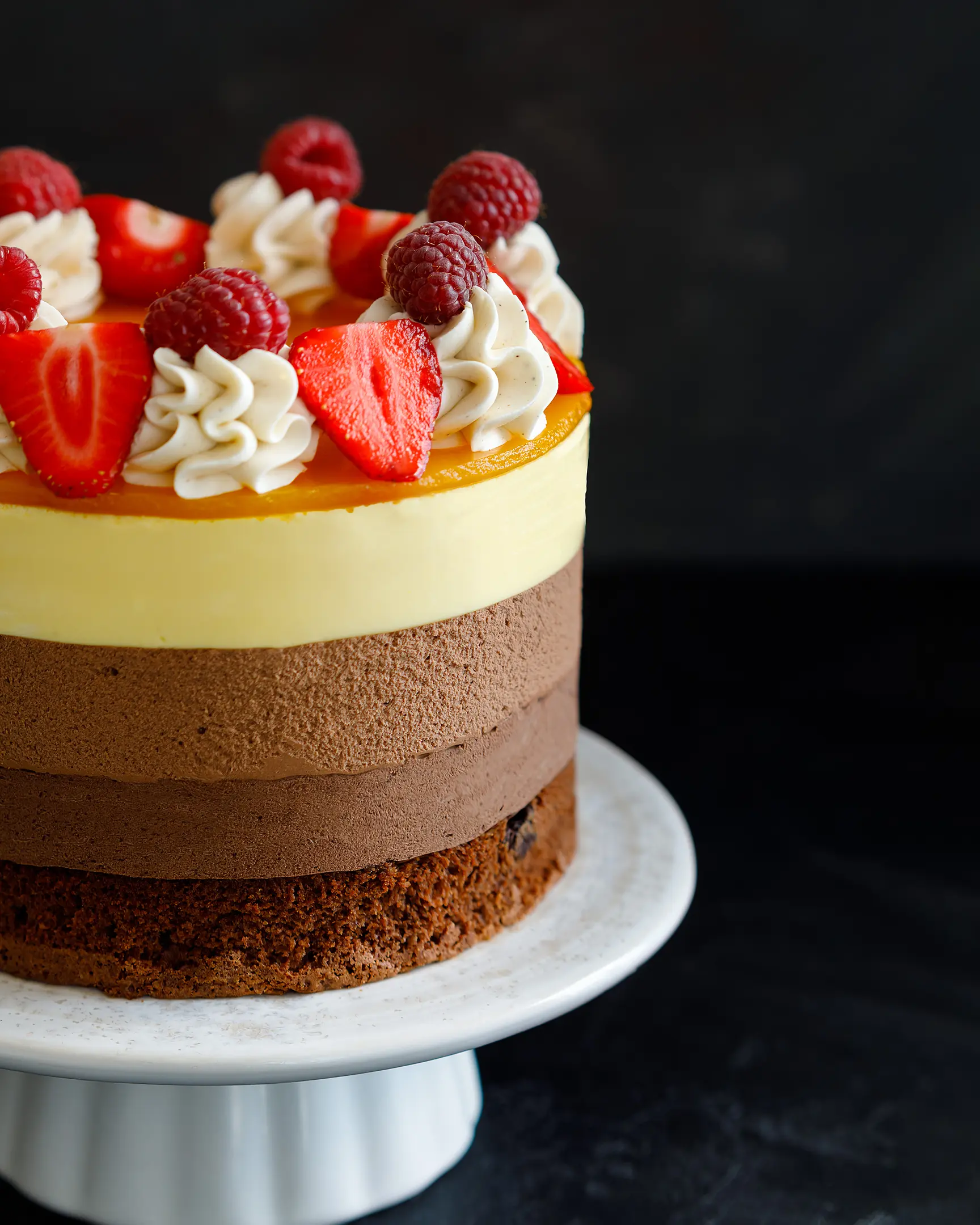 На снимката е торта от три шоколада. На снимката е торта от три шоколада. Виждат се и трите слоя с различни цветове. Тортата е украсена с малини и ягоди.