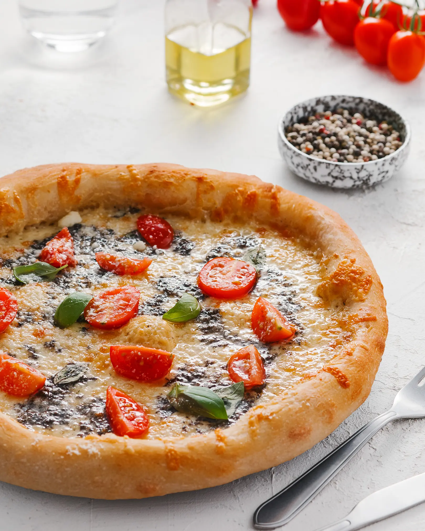 Пица на масата. На масата има пица с домати и сирен сос. Тя има красива хрупкава страна. Тя блести с масло в лъчите на светлината.