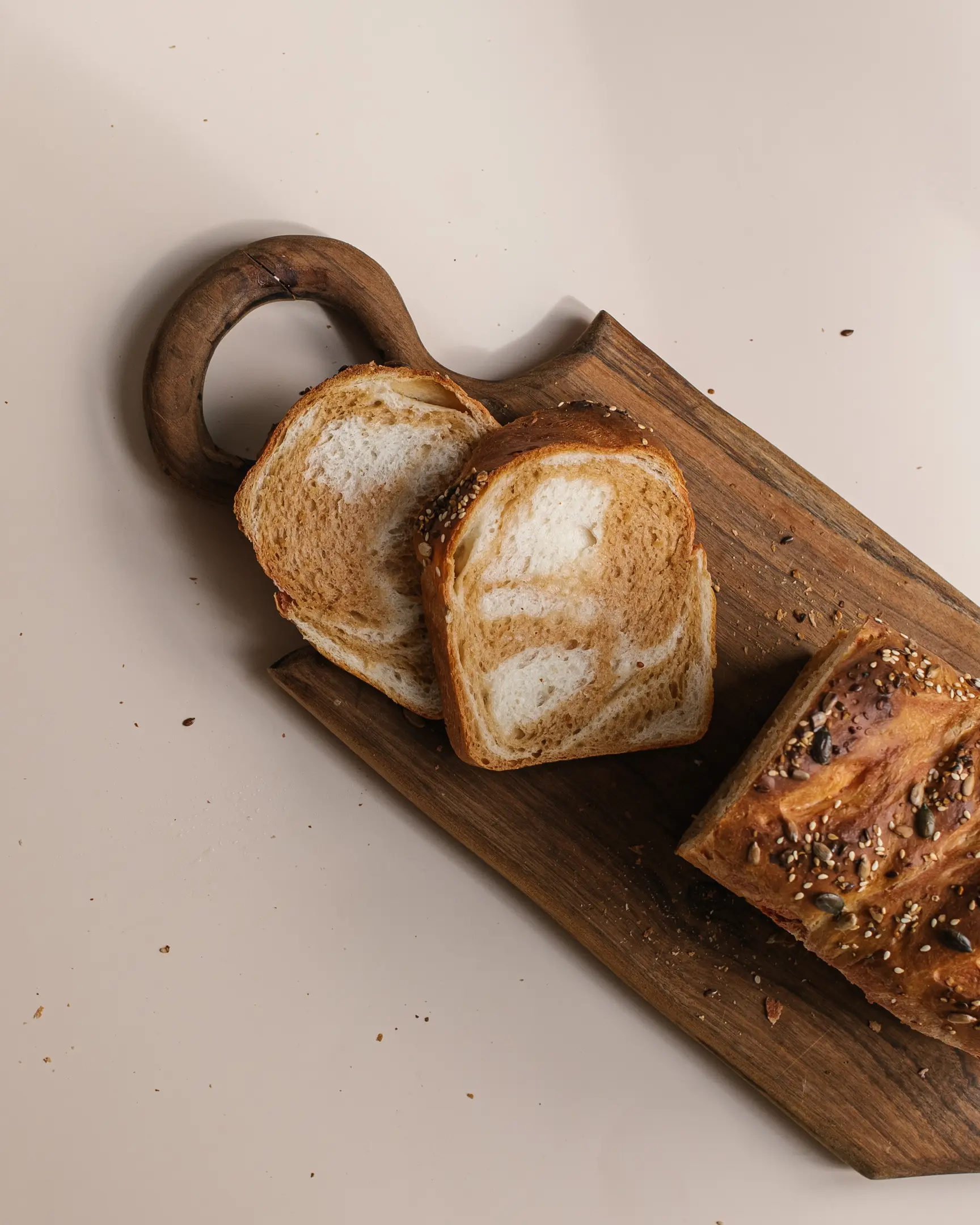На дървена поставка има хляб. На дървена поставка има хляб. Той е срязан. Виждат се линиите на прегъване на тестото. Поглед отгоре.