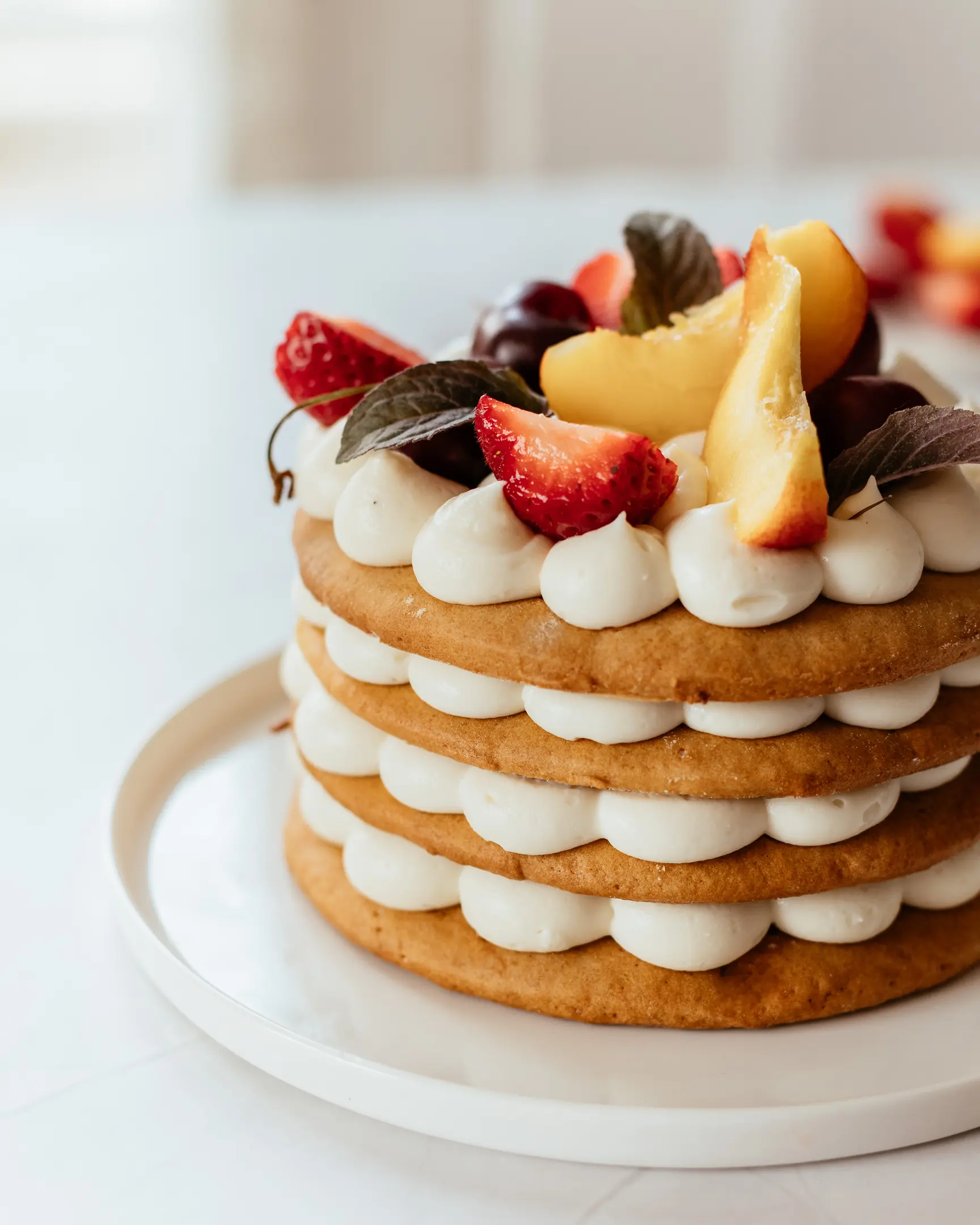 Слоеста медена торта. Слоеста медена торта, украсена с горски плодове, стои върху чиния.